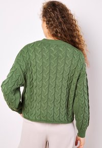 Grön stickad tröja med en strukturerad kabelmönster, långa ärmar och rundad halsringning, med en avslappnad passform och ribbade muddar.