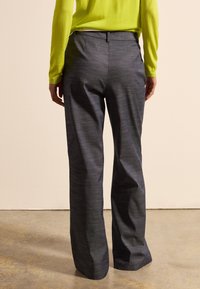 Graue weit geschnittene Hosen mit einer dezenten Textur und einer glatten Oberfläche, ausgestattet mit einem mittelhohen Bund und Gesäßtaschen.