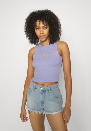 Top cropped em lavanda canelado com um recorte em forma de coração, combinado com calções de ganga azul claro, desbotados, com bordas desfiadas e fecho frontal com botão.