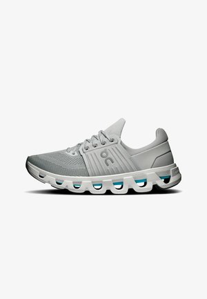 Chaussure de course gris clair avec tige en mesh, semelle blanche avec segments de coussin évidés et logo sur le côté.