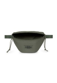 Riñonera Eastpak en verde oliva con tejido texturizado, cierre de cremallera y un parche de logo en la parte frontal. Cuenta con una correa ajustable en la parte trasera.
