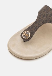 Infradito marroni con motivo, suola in suede beige e un accento con logo dorato MK emblematico sulla cinghia.