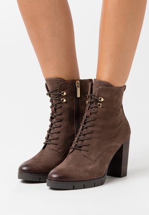 Botas de tobillo de cuero marrón con un acabado texturizado, parte delantera con cordones, cremallera lateral y tacón grueso. Presenta acentos en hardware en tono dorado.