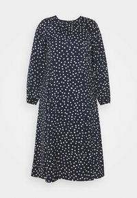 Navy-Kleid mit langen Ärmeln, Rundhalsausschnitt und Raffung. Hat weiße Punkte und eine fließende A-Linie. Weicher Stoff.
