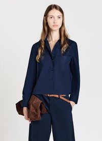 Navyblaues Langarmhemd mit Knopfleiste, Brusttasche und glattem Stoff; kombiniert mit braunem, strukturiertem Gürtel und weichem braunen Accessoire.