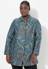 Dlouhý rukáv modrý s květinovým vzorem s jemnými detaily v hnědé a krémové barvě. Přední zapínání na knoflíky a špičatý límec. Hladká textura.