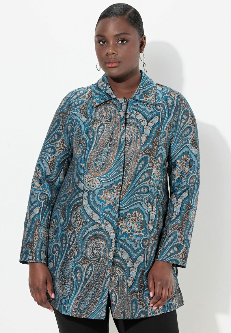 Dlouhý rukáv modrý s květinovým vzorem s jemnými detaily v hnědé a krémové barvě. Přední zapínání na knoflíky a špičatý límec. Hladká textura.