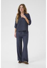 Top blu navy, morbido e con scollatura a V, maniche a 3/4 abbinato a pantaloni larghi coordinati; tessuto strutturato, cuciture a contrasto e scarpe casual.