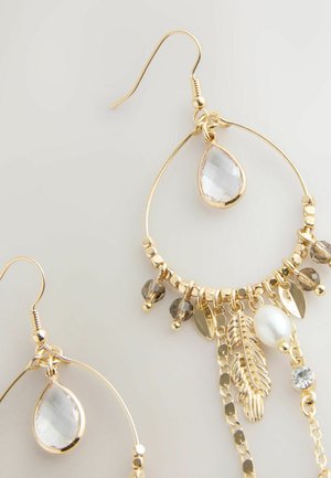 Goldene Creolen mit einem klaren tropfenförmigen Stein, facettierten Perlen, Metallblättern und einem detaillierten Federakzent, die ein geschichtetes Design präsentieren.