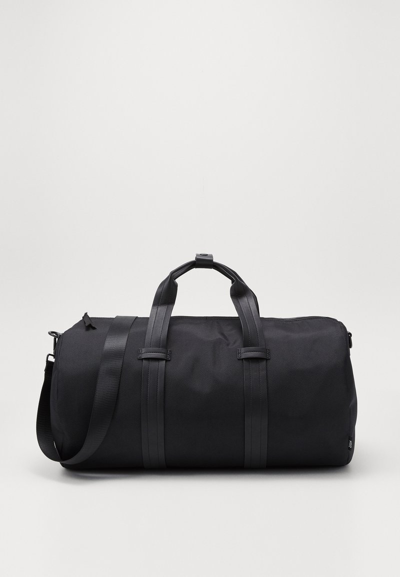 Bolsa de deporte negra hecha de nylon texturizado, con dos asas superiores, una correa de hombro desmontable y un diseño minimalista sin hardware visible.