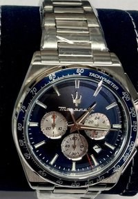 Klocka i rostfritt stål med blå tachymeterkrans, mörkblå urtavla, silverfärgade subdials och brun timvisare. Slät länkarmband.