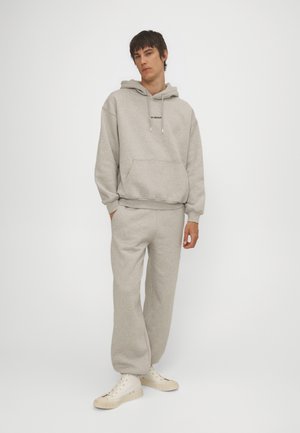 Grau Hoodie mit Fronttasche und verstellbaren Kordeln, kombiniert mit passenden Sweatpants. Beide bestehen aus weichem Stoff und haben einen entspannten Schnitt.