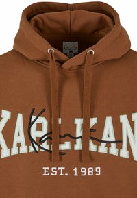 Felpa marrone con coulisse, caratterizzata dalla scritta "KAREKANE" in lettere bianche e verde chiaro, e "EST. 1989" in bianco. Materiale in misto cotone.