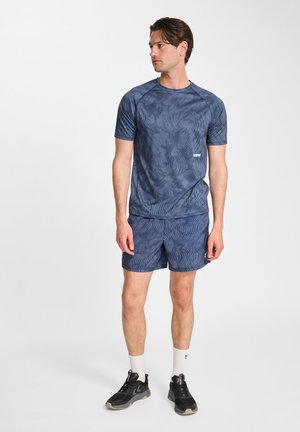 Marineblauw sportshirt met een textuurpatroon, korte mouwen, gecombineerd met bijpassende shorts. Model draagt zwarte sneakers en witte sokken.