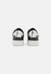 Baskets en cuir noir avec des accents métalliques argentés sur le talon et le logo, semelle en caoutchouc blanche et détails cloutés autour du col.