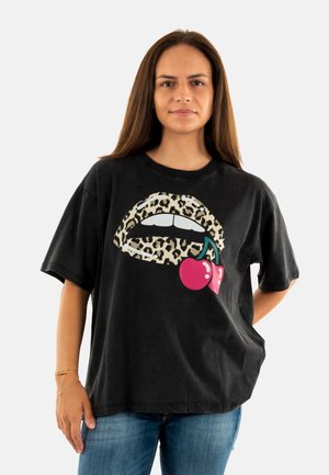 T-shirt en coton noir avec un motif de lèvres imprimées léopard et des cerises rouges. Coupe décontractée, manches courtes et col ras du cou.