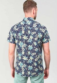 Camisa de manga corta en navy con un estampado floral que presenta flores en azul claro y crema. Fabricada con tejido ligero, de corte relajado.