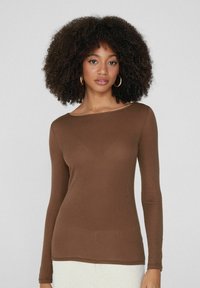 Langärmliges braunes Shirt aus weichem, elastischem Stoff mit Rundhalsausschnitt und tailliertem Design, das minimale Nähdetails aufweist.
