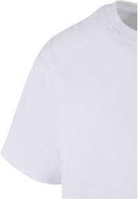 Tricou alb din bumbac, cu guler clasic și mâneci scurte. Textură netedă, design minimalist, fără modele vizibile sau detalii metalice.