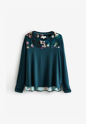Tricou cu mâneci lungi în nuanță de teal închis, cu un yoke cu motive florale. Material moale, guler rotund, tiv suprapus cu un imprimeu floral deschis la bază.