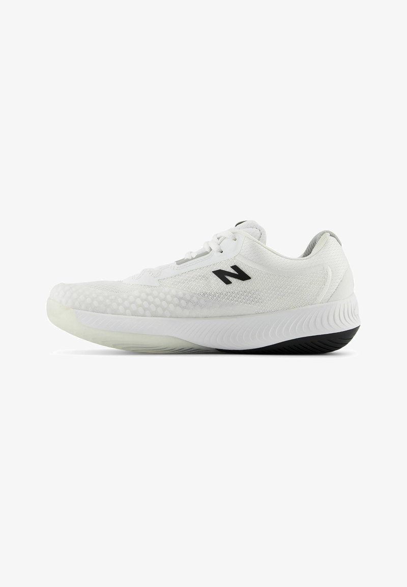 Zapatillas deportivas blancas con parte superior de malla texturizada, logo negro y suela de goma flexible que presenta una ligera curva y un patrón de tracción pronunciado.
