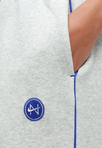 Γκρι φούτερ με κυκλικό μπλε κεντητό λογότυπο και μπλε περιμετρική ραφή. Μαλακό ύφασμα με λεία υφή.