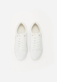 Białe syntetyczne trampki o gładkim wykończeniu, zaokrąglonym nosku i płaskim sznurowaniu. Wyraźne złote akcenty po bokach.