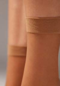 Beige knæhøje sokker med en glat tekstur og strikket øverste kant, der har en ensartet farve og et slankt design.