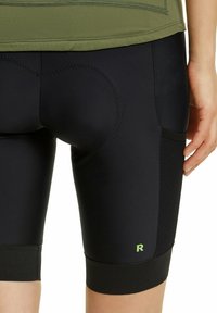 Pantaloni ciclistici neri con un design semplice, pannelli laterali testurizzati e un logo verde sulla parte inferiore della gamba. I pantaloni presentano una zona seduta imbottita.