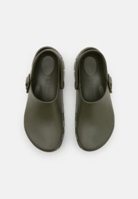 Zoccoli in gomma verdi con una superficie liscia, cinturino posteriore e fori di ventilazione sui lati; design minimalista, stile confortevole.