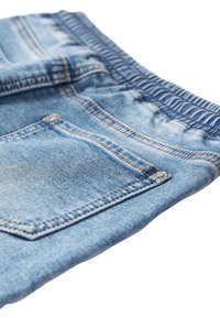 Svetlomodré rifľové šortky s elastickým pásom a viditeľným prešitím zadných vreciek na bielom pozadí.