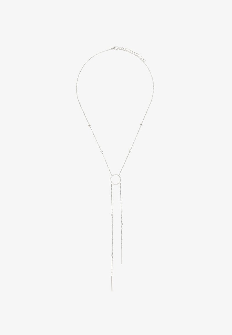 Srebrny naszyjnik z okrągłym wisiorkiem na środku. Dwie wydłużone łańcuszki opadają w dół, zdobione małymi gwiazdkami. Minimalistyczny design.