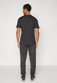 Sort T-shirt og matchende sweatpants, blanding af bomuld, slim fit, med korte ærmer og elastisk talje, parret med sorte sportsko.