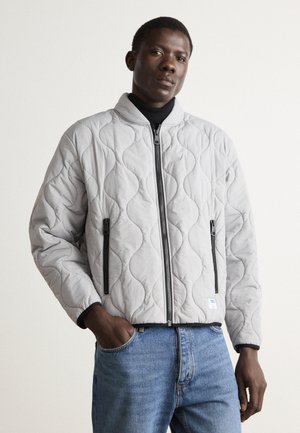 Light gray quilted bomber jacket with a stand collar, zip front, and black zipper accents. Features a textured, padded surface and elastic cuffs.