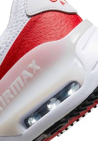 Adidași cu un superior texturat alb, accente roșii și o unitate de amortizare vizibilă, având o talpă transparentă și un model de talpă neagră.