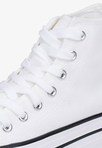 Sneaker alta in tela bianca con lacci bianchi piatti, occhielli in argento e suola in gomma nera. Presenta una texture liscia e un design minimalista.