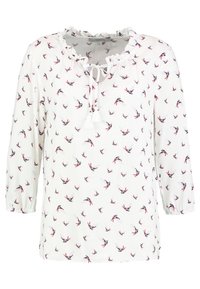 White blouse featuring an all-over pattern of small birds in red, blue, and black. Ruffled neckline, drawstring tie, and three-quarter sleeves.