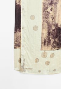 Tissu de couleur claire avec des motifs circulaires et des impressions florales abstraites et texturées foncées le long des bords et du coin.