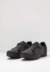 Černé cyklistické boty s texturovaným svrškem, síťovinovými panely a systémem uzavírání na kolečko. Mají robustní podrážku pro trakci v outdoorových podmínkách.