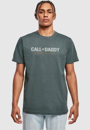 Camiseta de algodón verde oscuro con cuello redondo. Presenta texto en blanco y naranja: "OFICINAS DE PARENTALIDAD CALL of DADDY". Manga corta, corte relajado.