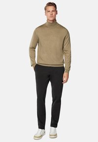 Beige turtleneck sweater with a ribbed texture, paired with black slim-fit pants and white sneakers featuring tan accents.
