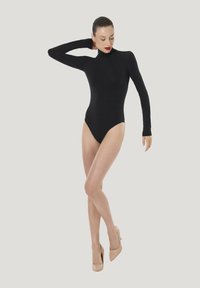 Svart långärmad bodysuit med hög krage; åtsittande silhuett och stretchigt material. Kombinerad med nakenfärgade högklackade skor.