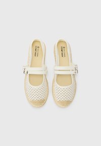 Baskets espadrilles blanches avec un design supérieur tissé et des sangles à double boucle. Comprend une semelle en corde naturelle et une doublure en tissu beige.