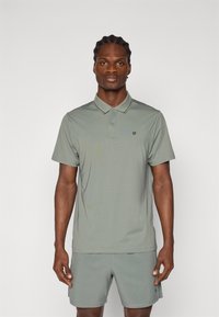 Lys grønn polo skjorte med krage og to knapper, med en subtil logo på venstre bryst. Glatt, pustende stoff; uformell design.
