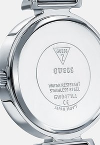 Roostevabast terasest kellatagune "GUESS" brändingu, veekindluse märgistuse, siledapinna ja ümmarguse kujuga. Näitab mudelinumbrit ja CE-märki.