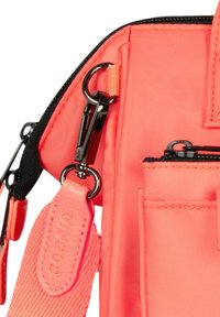 Koraal nylon tassectie met een zwarte metalen clip, gestructureerde schouderriem en meerdere vakken. Gladde oppervlakte met gedetailleerde stiksels.