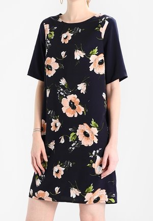 Robe courte à manches courtes en bleu marine avec des fleurs pêche et vertes. Tissu doux avec un col rond et une coupe décontractée. Longueur au-dessus du genou.