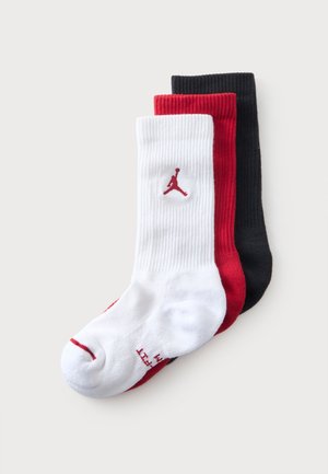 Trois chaussettes montantes côtelées empilées en blanc, rouge et noir, avec un logo Jumpman rouge sur la chaussette blanche.