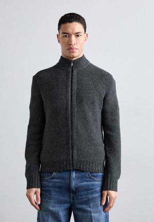 Suéter gris de cremallera con cuello alto y puños acanalados. Hecho de una tela texturada, presenta un color sólido y un diseño ajustado.