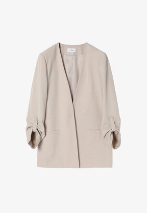 Lys beige blazer med V-halsudskæring, trekvartærmer med knapdetaljer og to forlommer. Glat materiale med en struktureret design.